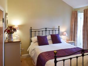 a bedroom with a large bed with purple pillows at High Dalton Hall Cottage in Newsham