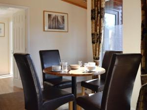 einen Tisch mit schwarzen Stühlen, einem Tisch und einem Fenster in der Unterkunft Lodge F- Uk33092 in Dinnet
