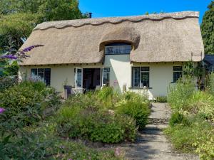 un vecchio cottage con tetto di paglia in un giardino di The Cottage a Lane to Richards Castle