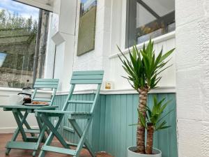 2 Stühle und ein Tisch auf einer Veranda mit einer Palme in der Unterkunft Hollybank in Ladybank