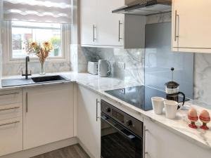 a kitchen with white cabinets and a sink at Hollybank in Ladybank