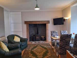 a living room with a fireplace and a couch and chairs at Ballygroggan Farmhouse - Uk35208 in Machrihanish