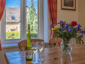 a bottle of wine and glasses on a table with flowers at Ashby Cottage in Long Compton