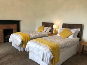 two beds in a room with a fireplace at Ballygroggan Farmhouse - Uk35208 in Machrihanish