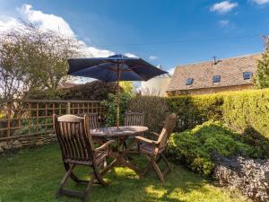 a table with two chairs and an umbrella at Ashby Cottage in Long Compton
