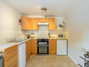 a kitchen with wooden cabinets and a stove top oven at Coach House - Uk33307 in Mellis