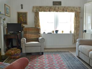 a living room with a chair and a window at The Cottage in Duirinish