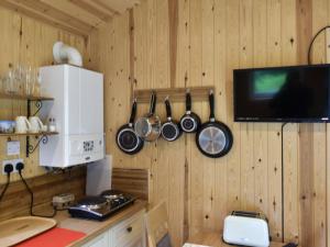 - une cuisine avec une télévision, des casseroles et des poêles au mur dans l'établissement Shepherds Hut 2 At Laddingford - Uk32534, à Yalding