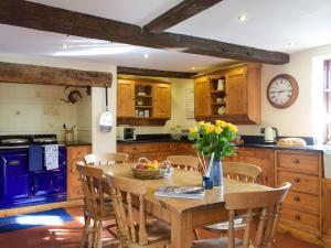 a kitchen with a wooden table and chairs and a clock at Grafton Farm in Loppington