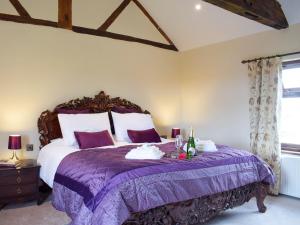 a bedroom with a large bed with a purple bedspread at Grafton Farm in Loppington