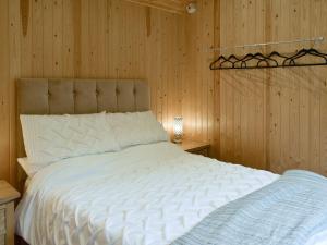 a bedroom with a large white bed with wooden walls at Shepherds Hut 2 At Laddingford - Uk32534 in Yalding