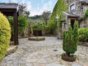 a stone courtyard with trees and a building at Garden Cottage in Sabden