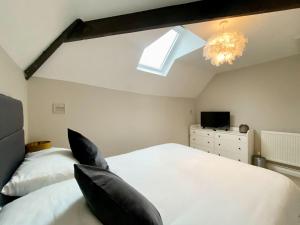 een slaapkamer met 2 witte bedden en een dakraam bij The Corner Barn in Cirencester