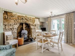 a dining room with a table and a stone fireplace at Holly Tree Cottage in Tain