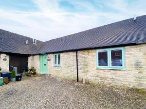 a brick house with a green door and a driveway at The Corner Barn in Cirencester