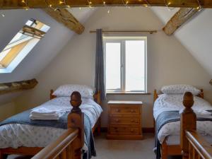 2 Einzelbetten in einem Dachzimmer mit Fenster in der Unterkunft The Coach House in Lydney