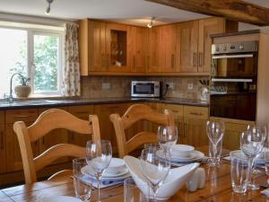 een keuken met een houten tafel met wijnglazen erop bij The Coach House in Lydney