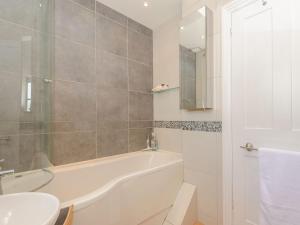 un bagno bianco con vasca e lavandino di Number 1 Admiralty Cottages ad Alverstoke