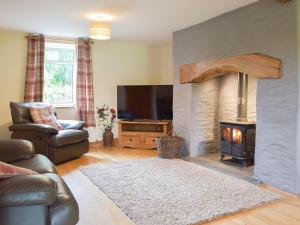 a living room with a fireplace and a television at Typicca Farmhouse in Brechfa