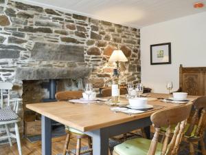 a dining room with a table and a stone wall at Seaton Cottage in Collieston