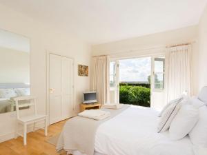 a white bedroom with a white bed and a window at Graham Cottage in Thurning
