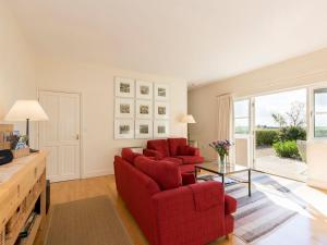 a living room with two red chairs and a table at Graham Cottage in Thurning