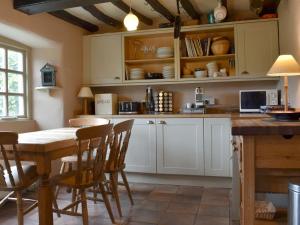 a kitchen with white cabinets and a table and chairs at Thorn Cottage in Spark Bridge