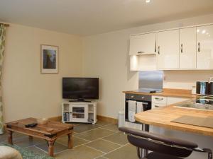 a kitchen with white cabinets and a table and a tv at Oak Lodge in Edwin Loach