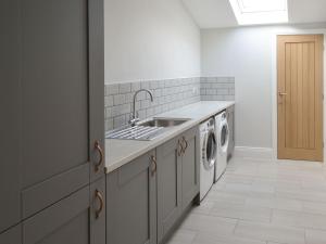 a kitchen with a sink and a washing machine at The Hemmel in Greenhaugh