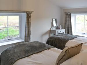 two beds in a bedroom with two windows at The Hemmel in Greenhaugh