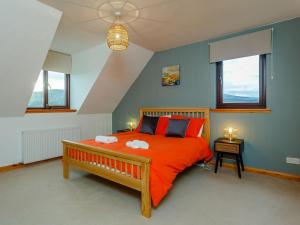 um quarto com uma grande cama laranja com almofadas vermelhas em The Big Hoose em Achnahanat