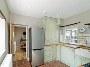 a kitchen with white cabinets and a refrigerator at Pinfold Cottage in Richmond