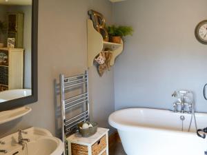 a bathroom with a tub and a sink and a mirror at Townhead Cottage in Alwinton