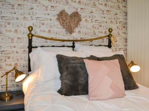 ein Schlafzimmer mit einem Bett mit weißen Kissen und einer Ziegelwand in der Unterkunft Townhead Cottage in Alwinton