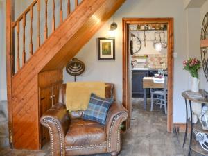 einen Ledersessel in einem Wohnzimmer mit einer Treppe in der Unterkunft Townhead Cottage in Alwinton