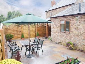 a patio with a table and chairs and an umbrella at The Byre in Pencombe