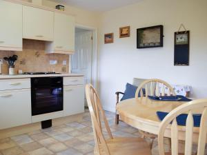 cocina y comedor con mesa y sillas en The Byre en Pencombe