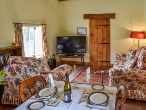 a living room with a couch and a table with a bottle of wine at Bradcar Farm Cottage in Snetterton
