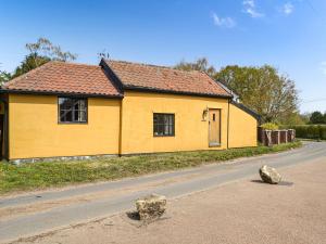 a yellow house on the side of a road at Bradcar Farm Cottage in Snetterton