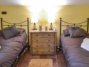 a bedroom with two beds and a night stand with two lamps at Bradcar Farm Cottage in Snetterton