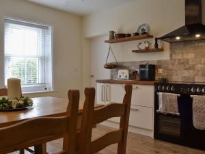 cocina con mesa de madera, mesa y fogones en Blaithwaite Cottage, en Blencogo