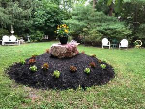 a flower garden with a vase on a rock at Relax in Nature & Serenity at Bird River Cottage! in Middle River