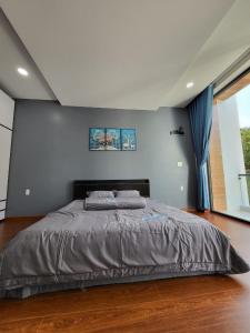 a large bed in a bedroom with a blue wall at T Home BMT in Buon Ma Thuot