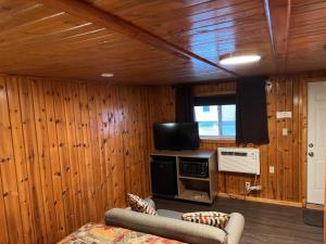 a living room with wood paneled walls and a television at Sunset Motel of St. Ignace in Saint Ignace