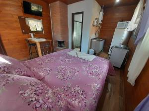 1 dormitorio con 1 cama con edredón rosa en Cabanas dos Pinheiros, en São Francisco de Paula