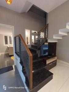 a living room with a staircase with a television at Peppercorn Cottage, Vythiri. in Vythiri