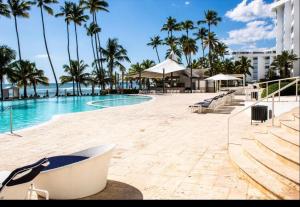 Marbella Juan dolio beach front luxury apartment في خوان دوليو: مسبح بالنخيل ومنتجع