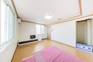 een grote kamer met een paars tapijt op een houten vloer bij Remember Youth Hostel in Gyeongju
