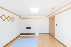 een lege kamer met een witte muur en een koelkast bij Remember Youth Hostel in Gyeongju