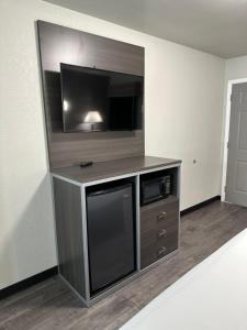 a entertainment center with a flat screen tv in a hotel room at Sleepy Traveler Motel in Wagoner